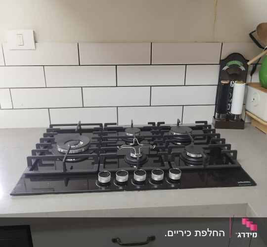 כיריים גז מובנות מזכוכית שחורה מותקנות על משטח שיש במטבח